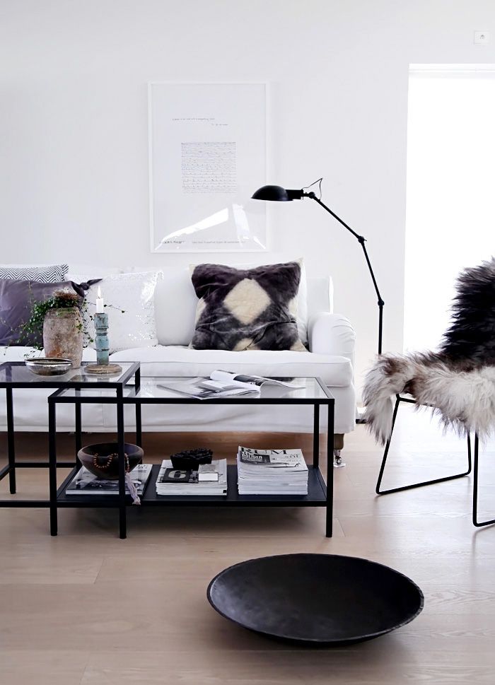 a living room filled with furniture and a white couch in front of a wall mounted lamp