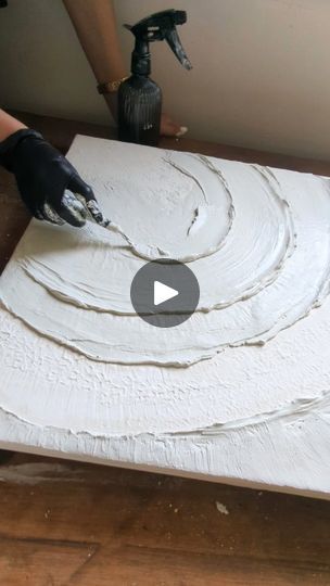 a person is painting a piece of white paper with black paint on it and another hand in the background