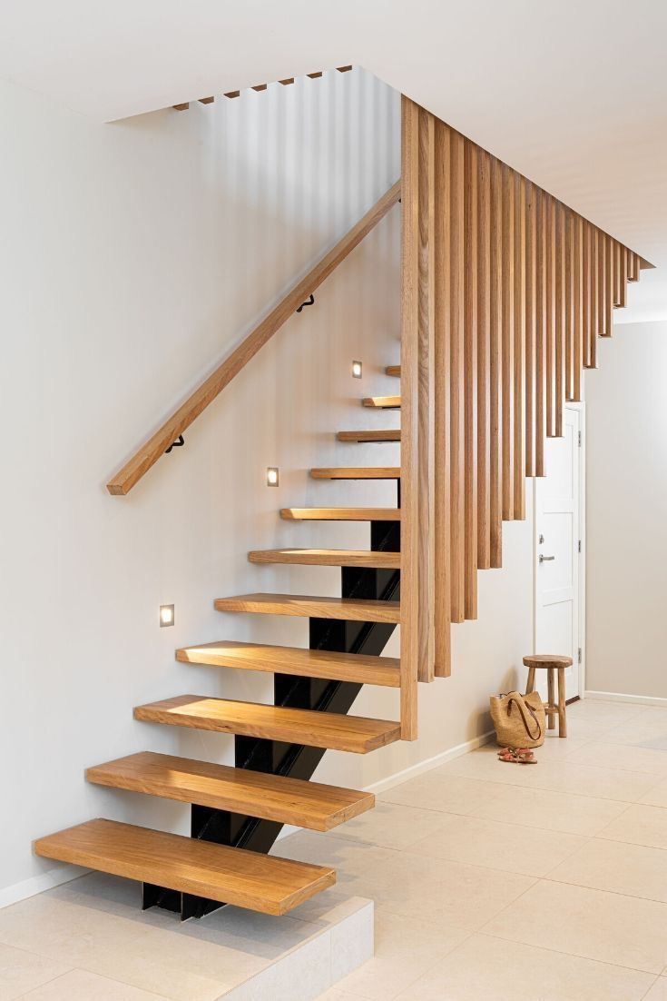 there is a wooden stair case in the house with white walls and flooring on it