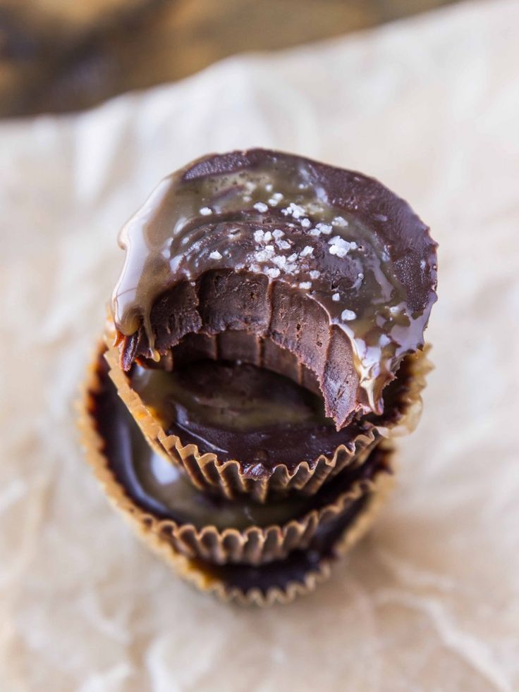 three chocolate covered cupcakes sitting on top of a piece of parchmented paper