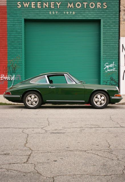 a green sports car parked in front of a garage door