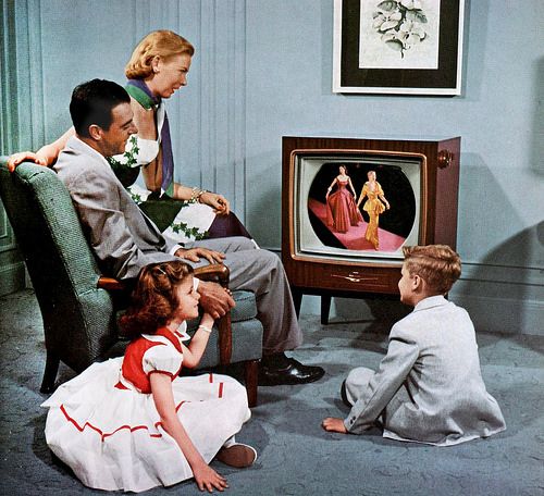 three children sitting in front of a tv with their parents watching them on the screen