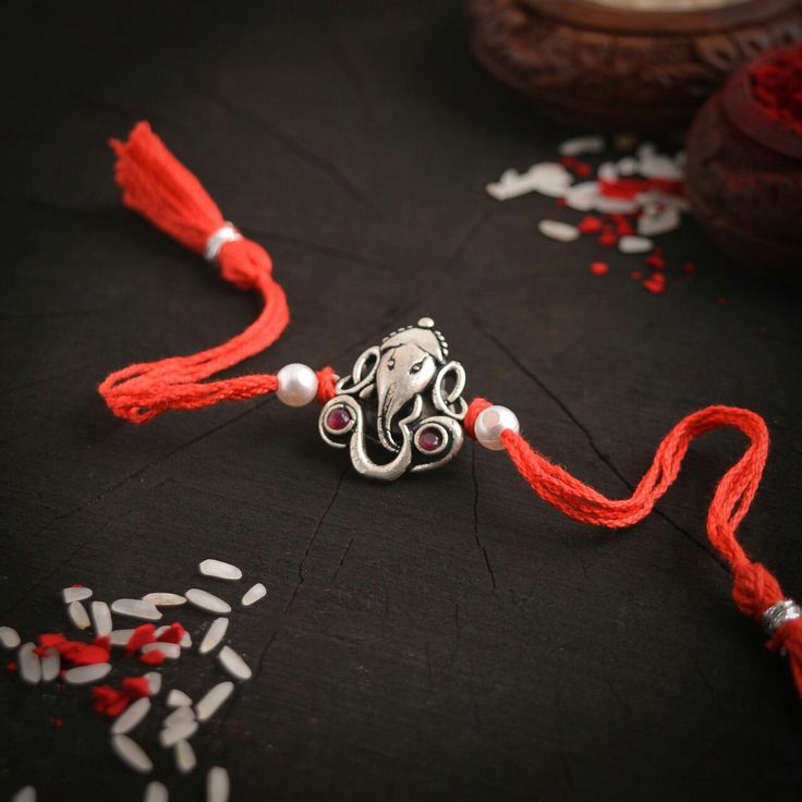 an octopus necklace is adorned with red string and beads on a black tablecloth surrounded by confetti