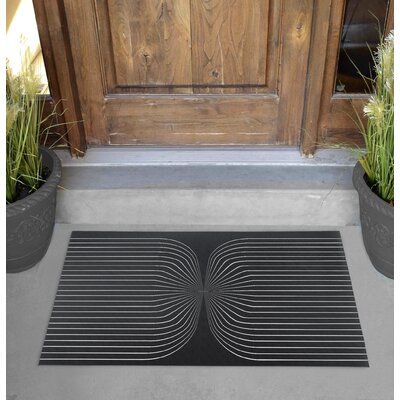 a door mat that is on the ground near some potted plants and a wooden door