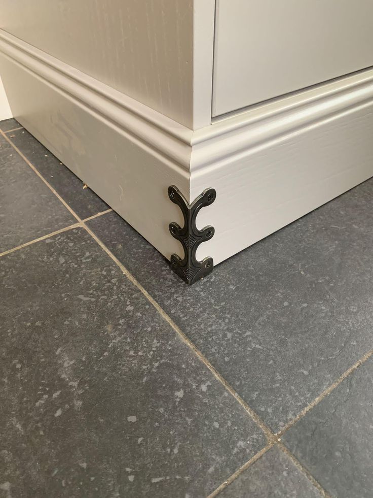 the corner of a room with tile flooring and door handle on it's side