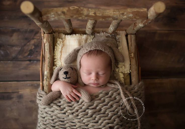 a baby sleeping in a basket with a teddy bear