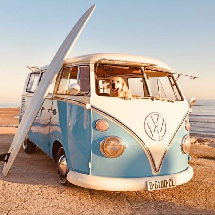 a blue and white vw bus with a surfboard attached to it