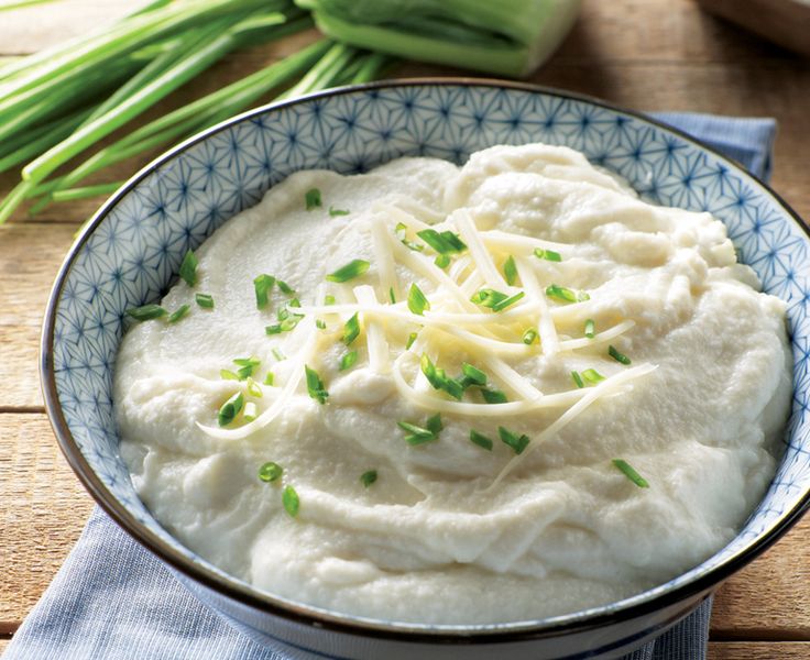 a bowl filled with mashed potatoes on top of a blue and white cloth next to celery stalks