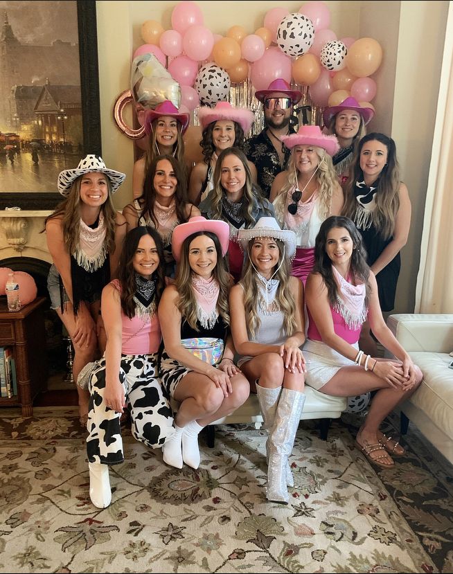 a group of women dressed up in costumes posing for a photo with balloons and decorations behind them