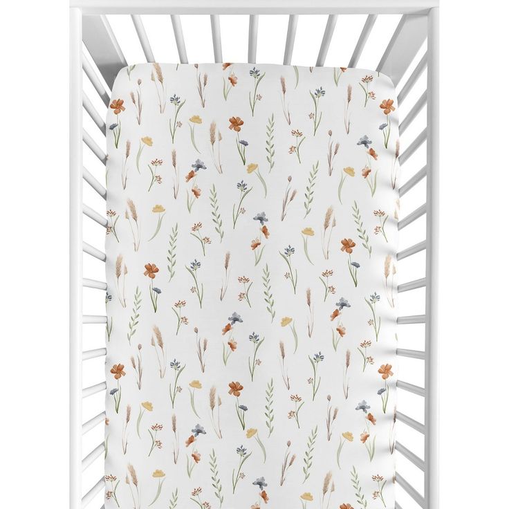 a white crib with flowers and leaves on the sheet in this nursery bedding set