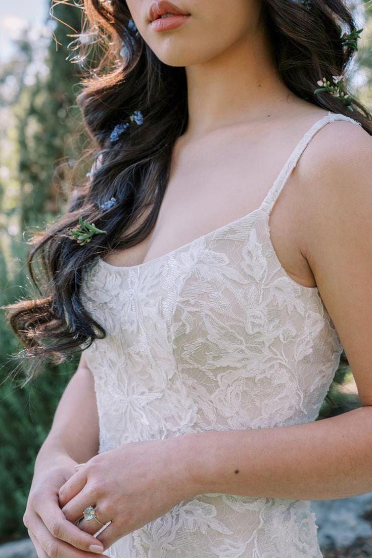 a woman in a white dress with flowers on her head wearing a flower crown and looking off to the side