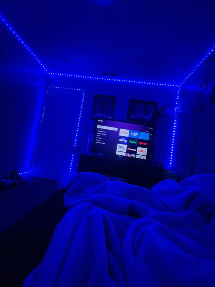 a bedroom with blue lights and a flat screen tv on the wall in the corner