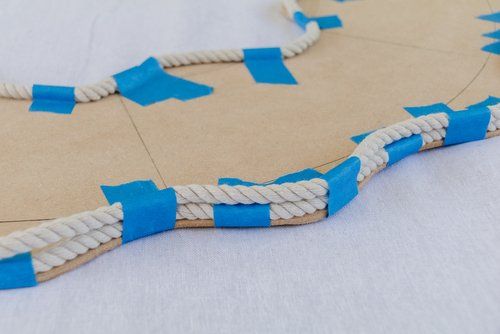 a piece of cardboard with blue tape on it and some white string attached to it