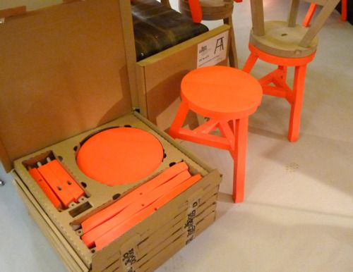 an open box with orange plastic parts in it next to two chairs and stools