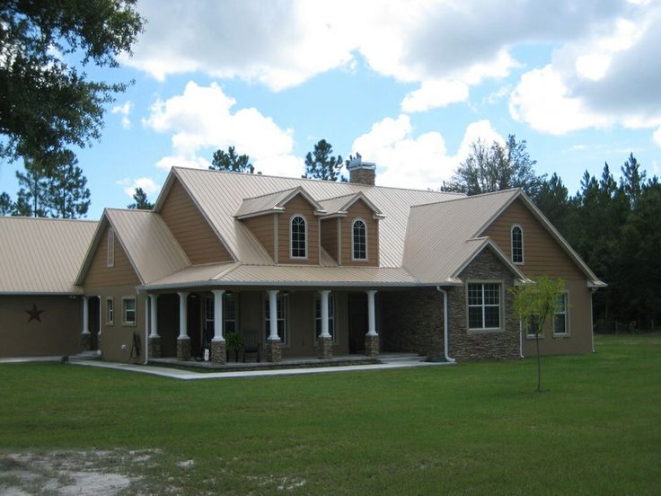 a large brown house sitting on top of a lush green field