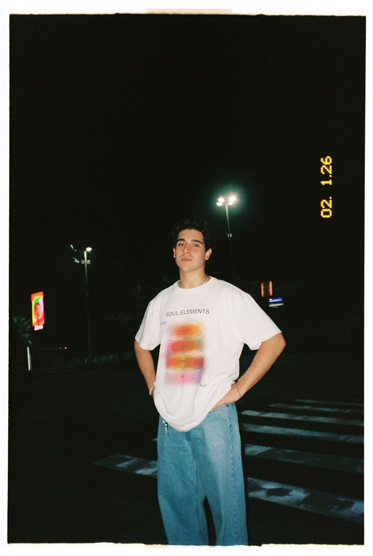 a man standing in the middle of a parking lot at night with his hands on his hips