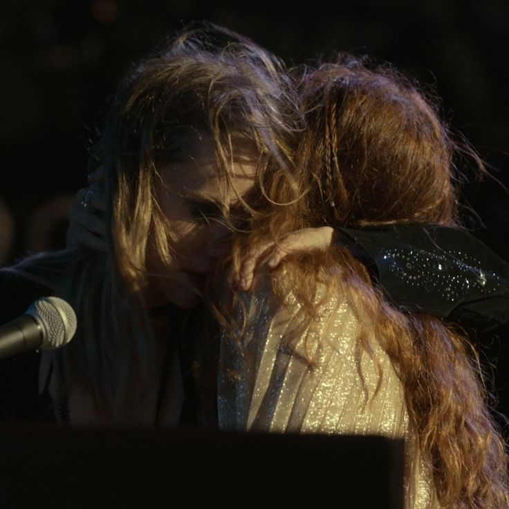 a woman with long hair covering her face in front of a microphone