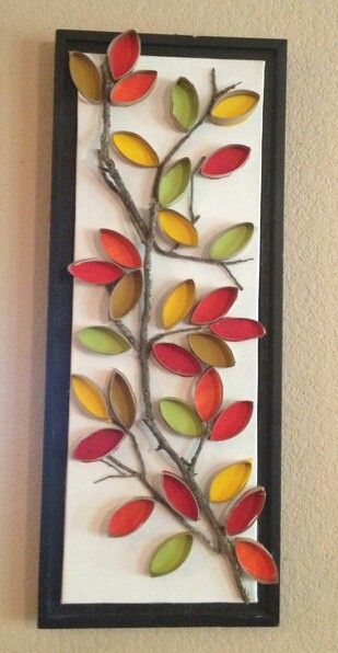 a decorative wall hanging made out of paper and metal branches with colorful leaves on it