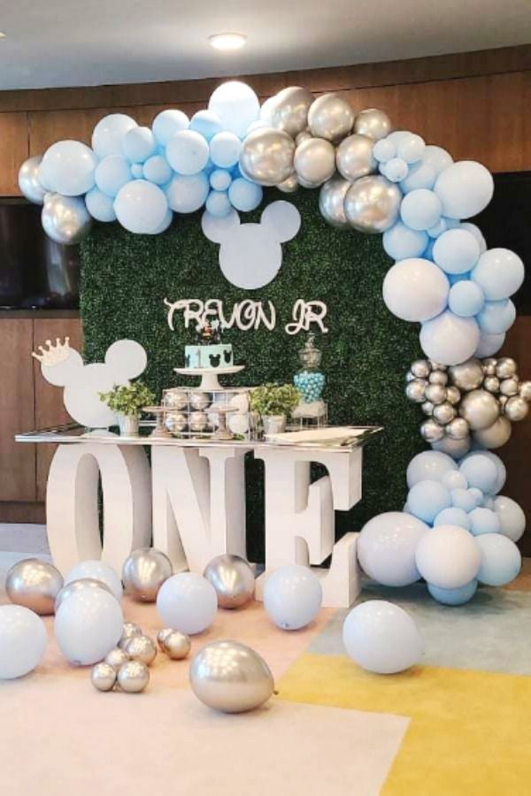 a table with balloons, cake and decorations for a one year old baby shower party