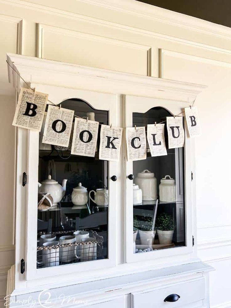 an old china cabinet is decorated with books and teapots for the book club