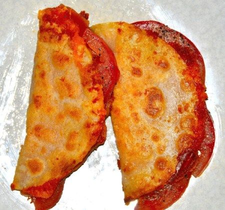 two slices of pizza sitting on top of a white paper covered plate with pepperoni and cheese