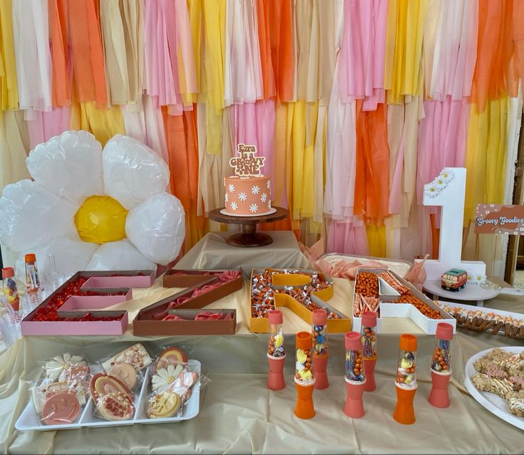 an assortment of desserts and sweets displayed on a table in front of colorful streamers