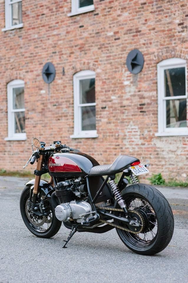 a red and black motorcycle parked in front of a brick building