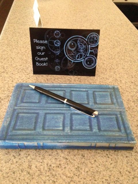 a pen sitting on top of a blue tile covered counter next to a sign that says please stop guest book