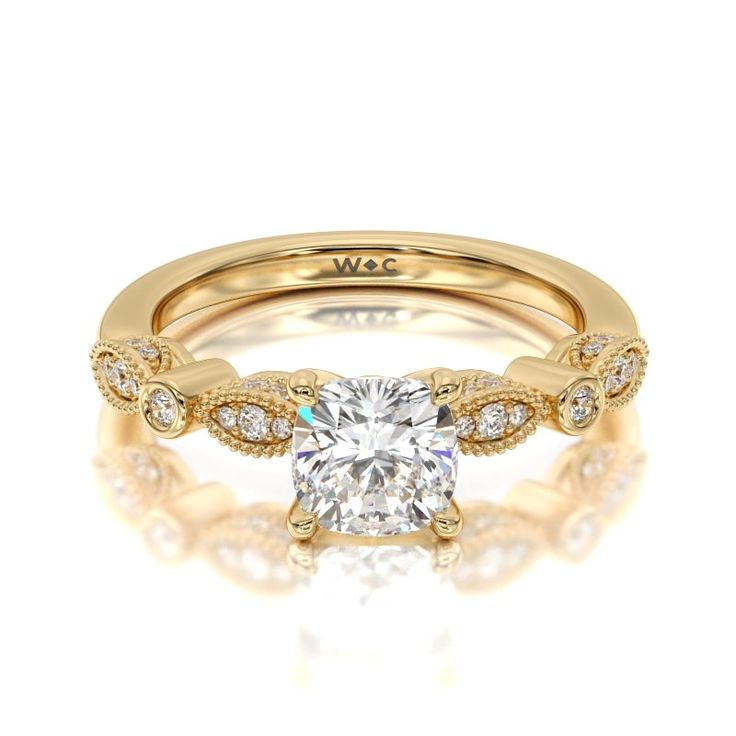 a yellow gold engagement ring with a cushion cut diamond in the center and side stones