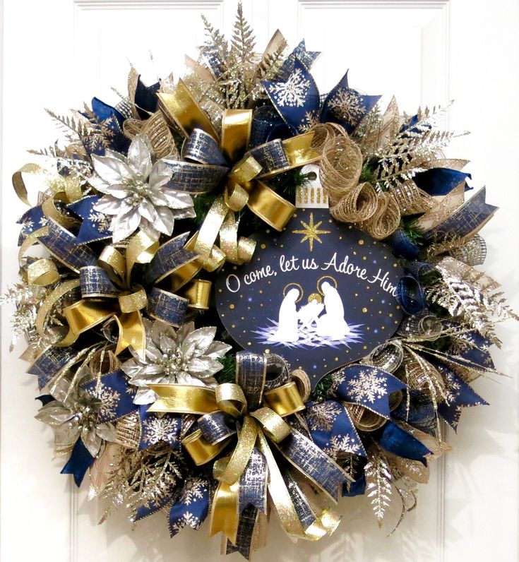 a christmas wreath on the front door with gold and blue ribbons, snowflakes, and a nativity scene