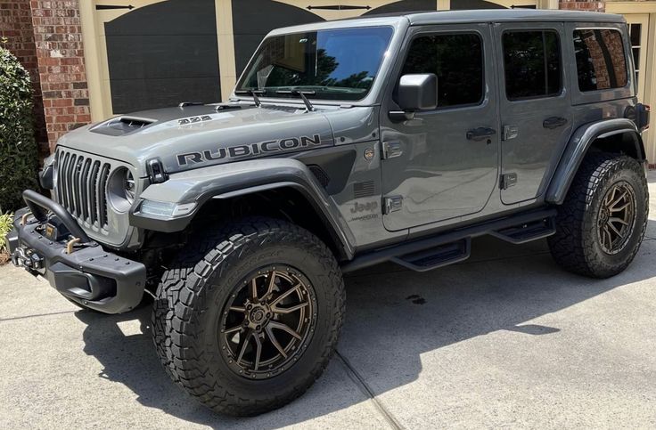 a gray jeep parked in front of a brick building with black lettering on the side