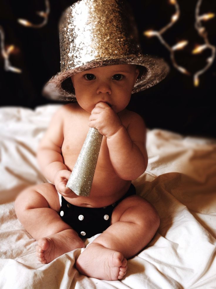 a baby sitting on a bed wearing a hat