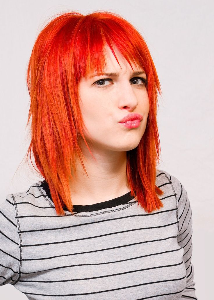 a woman with red hair is making a funny face while wearing a striped shirt and looking at the camera