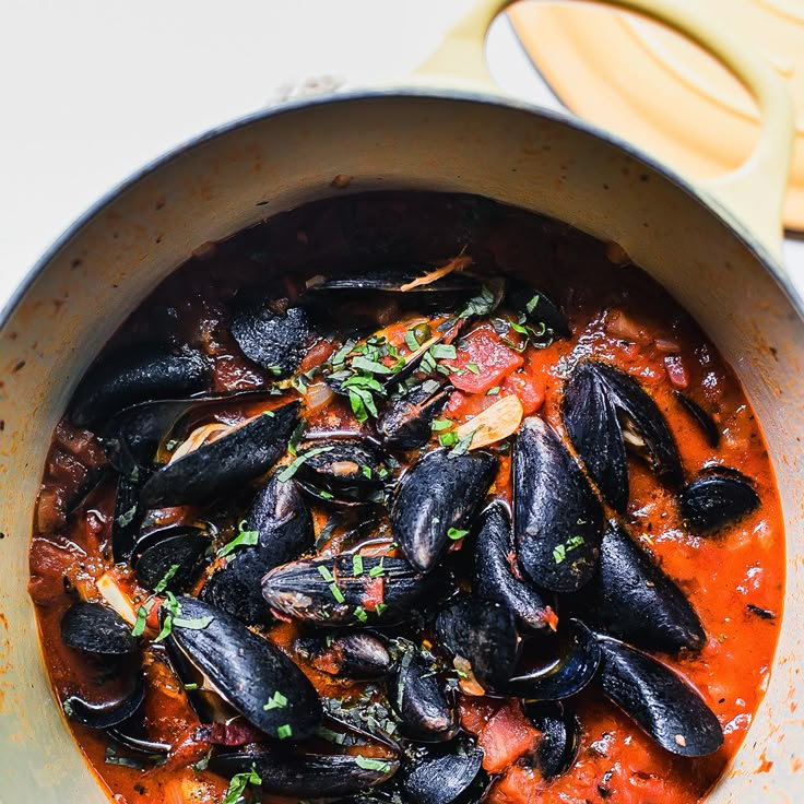 a pot filled with mussels and sauce on top of a table