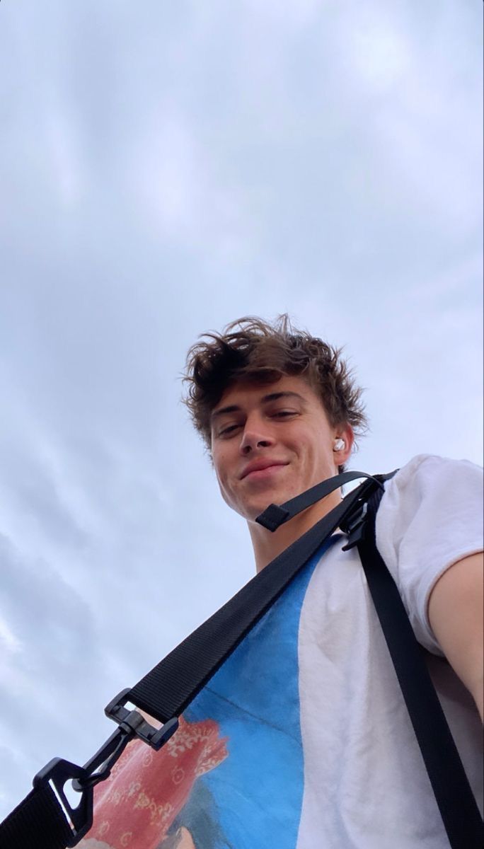 a young man with a camera strap around his neck looking at something in the sky