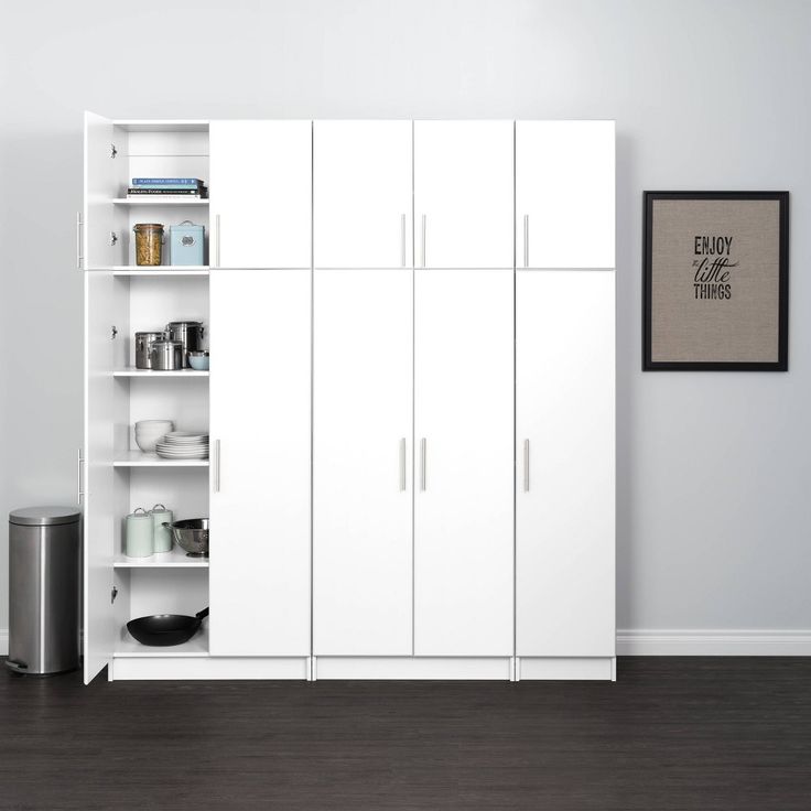 an empty room with white cupboards and a black trash can on the floor in front of it