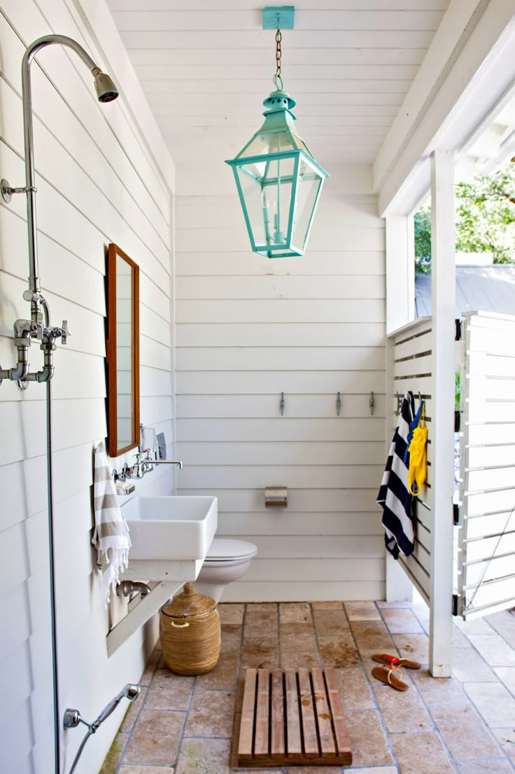 a white bathroom with two sinks and a green lantern hanging from the ceiling above it