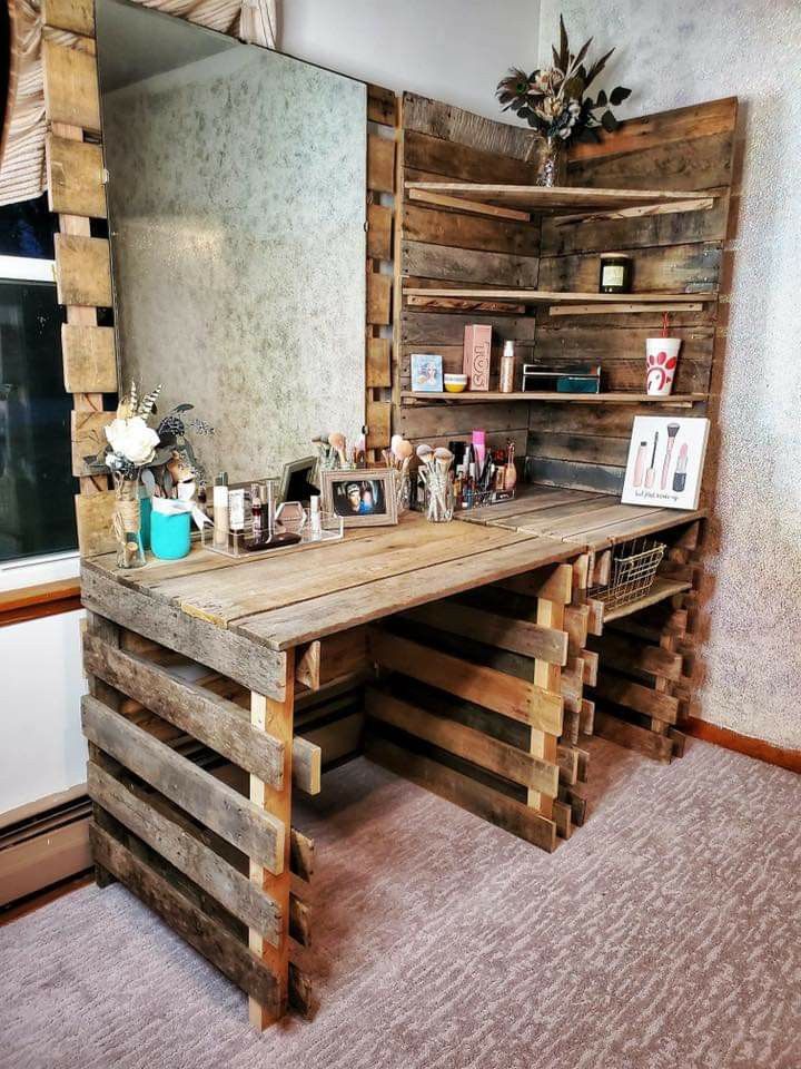 a desk made out of wooden pallets in front of a large mirror and shelves