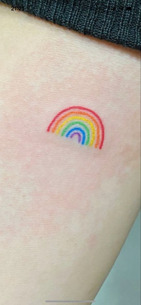 a small rainbow tattoo on the back of a woman's thigh