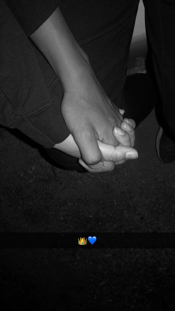 two people holding hands on the ground with a heart shaped sticker in front of them