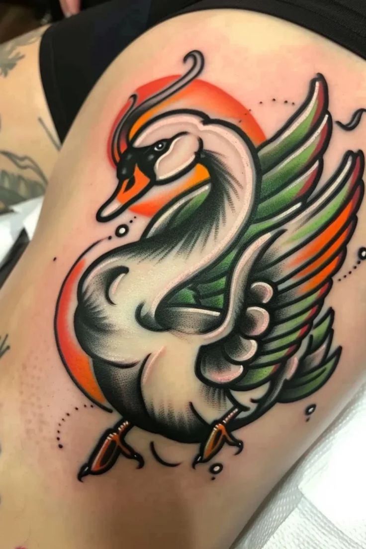 a woman's thigh with a tattoo of a swan and an orange sun on it