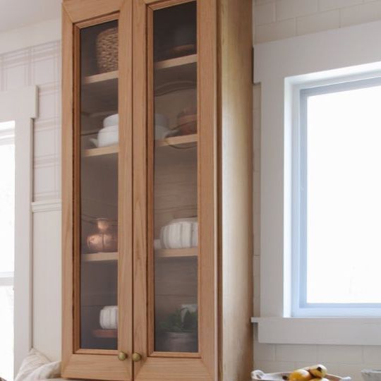 a wooden cabinet with glass doors in a kitchen