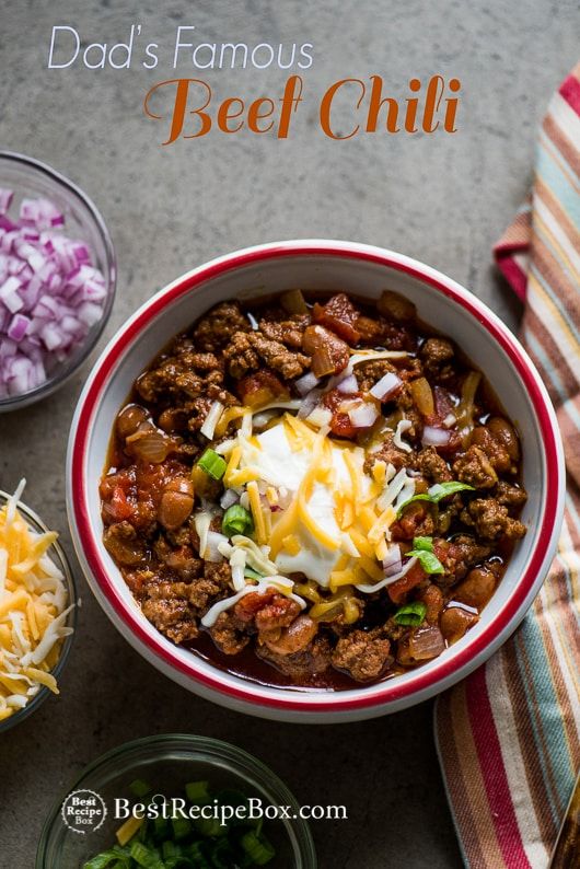 a bowl filled with chili, cheese and onions