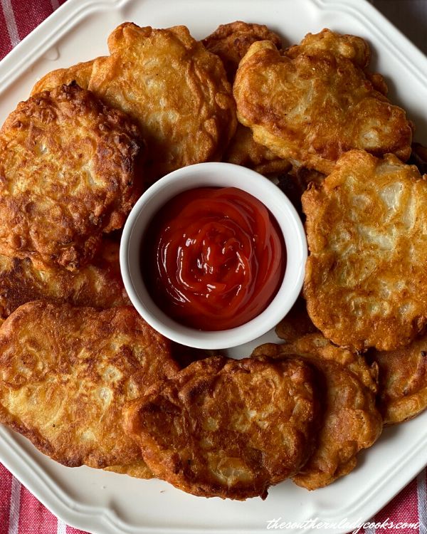 some fried food on a white plate with ketchup and sauce in the middle