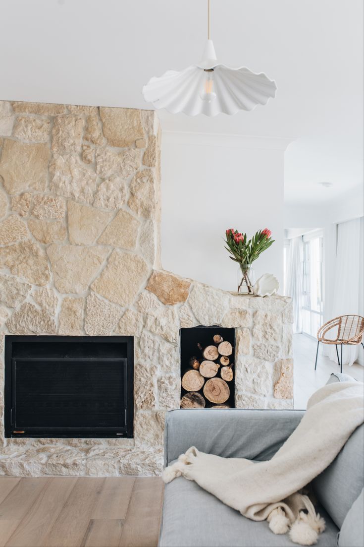 a living room filled with furniture and a fire place in front of a stone wall