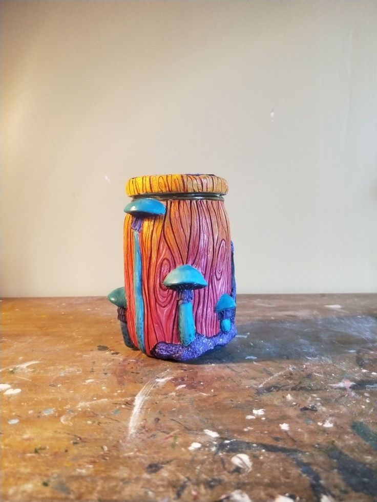 a colorful jar sitting on top of a table next to a white wall and floor