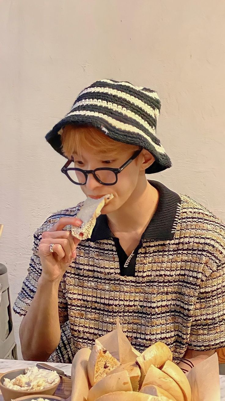 a person sitting at a table with some food in front of him and eating bread