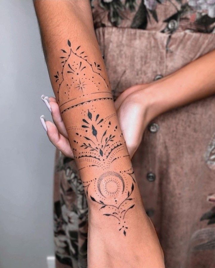 a woman's arm with tattoos on it and her hand holding the other arm