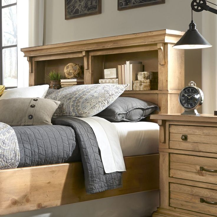 a bed sitting next to a wooden dresser with drawers on each side and an alarm clock