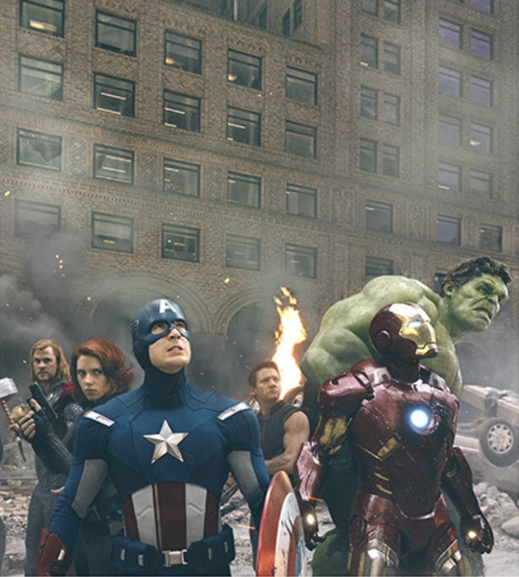 the avengers are standing in front of an old building with fire coming out of it